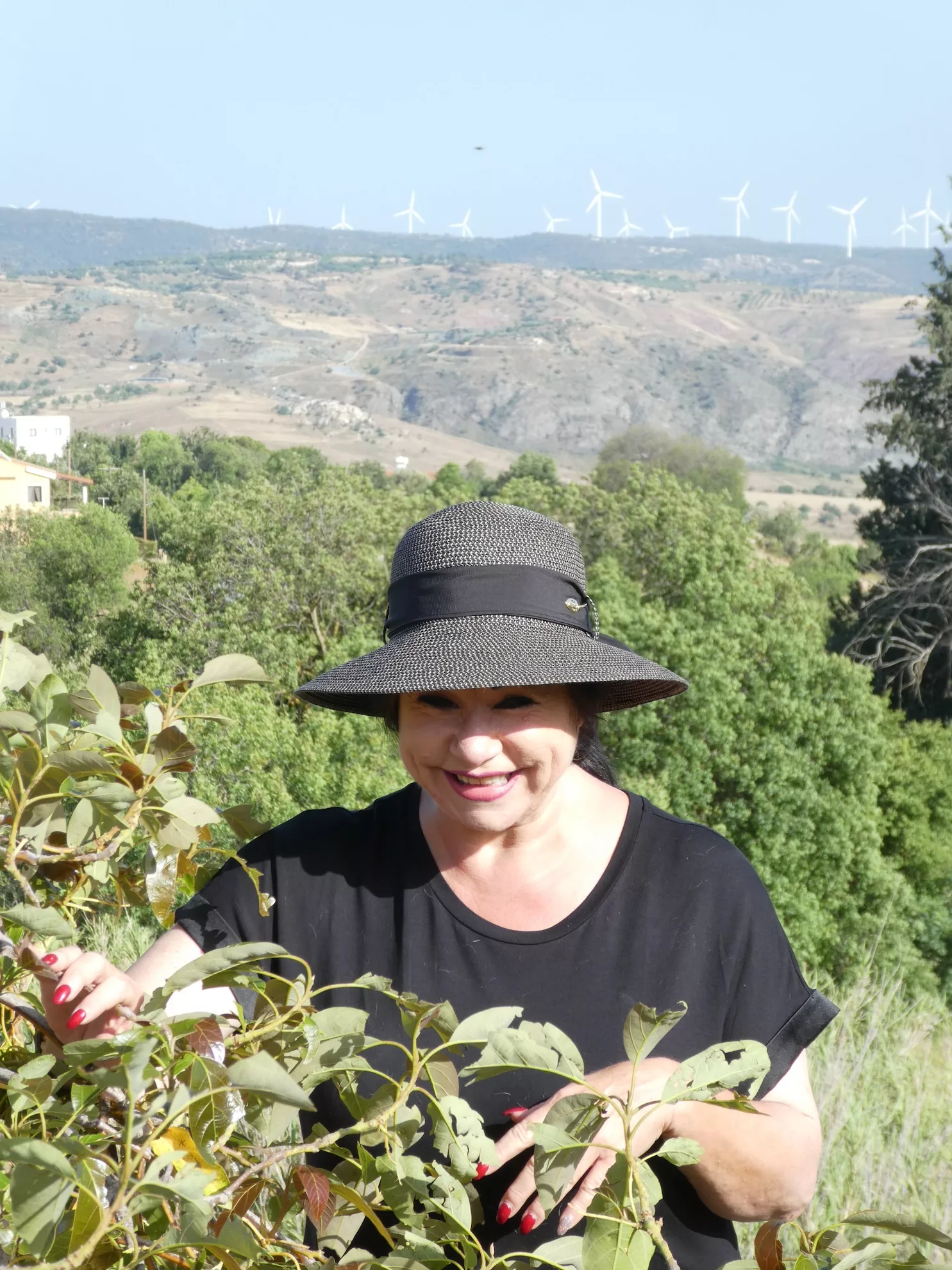 Sabine Kuhn mit Sonnenhut lacht inmitten der zyprischen Hügellandschaft