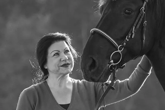 Schwarz-Weiß-Porträt: Sabine Kuhn mit einem ihrer Pferde, dem sie liebevoll zugewandt ist